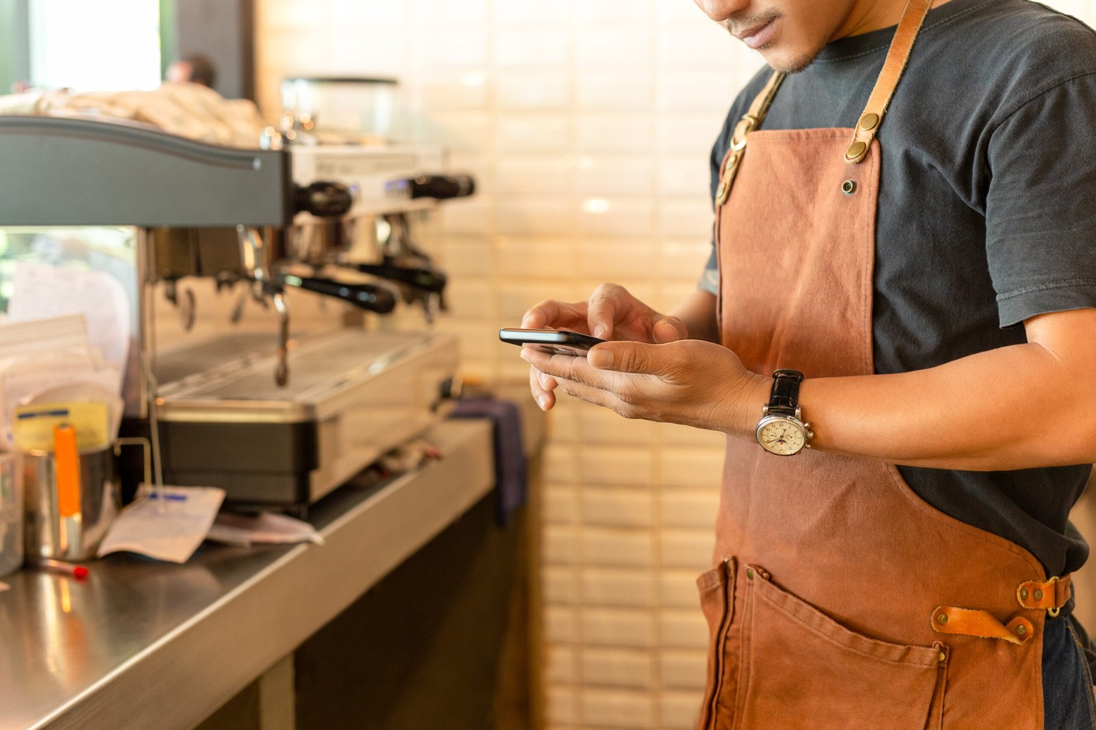 Barista checking cell phone in coffee shop