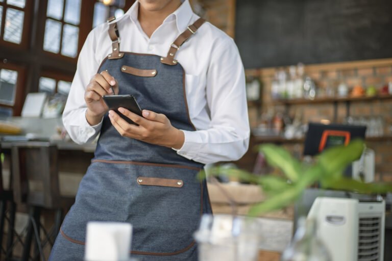 Waiter using touch pad or smart phone to send customer order in the restaurant. Modern wireless technology for retaurant or coffee shop